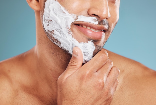 Czyszczenie kremu do golenia i pianka z mężczyzną do makiety zdrowia urody i dobrego samopoczucia na niebieskim tle studia Mężczyzna zadowolony z pielęgnacji twarzy dla czystej i zdrowej skóry z depilacją i samopielęgnacją