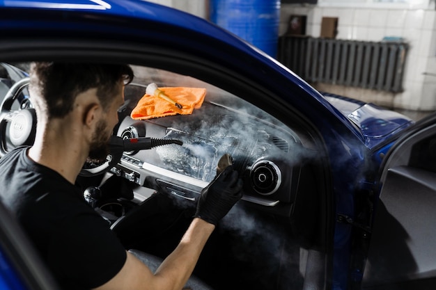 Czyszczenie pianą i detergentem w samochodzie za pomocą pary Pracownik w serwisie autoczyszczenie czyste wnętrze samochodu Detale wnętrza samochodu