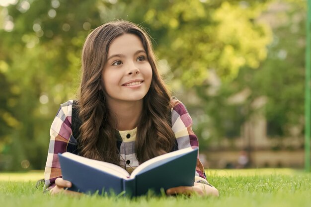 Czytanie pomaga rosnąć twojemu ziarnu wiedzy Szczęśliwe dziecko czyta książkę leżąc na zielonej trawie Dzień wiedzy 1 września Powrót do szkoły Edukacja podstawowa Biblioteka szkolna Klub pozaszkolny Rozwiń swój umysł