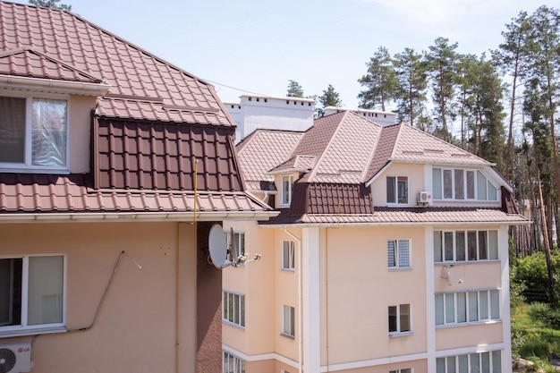 Dach na nieruchomości mieszkalnej z nową brązową dachówką z blachy falistej. Nowoczesny metalowy dach. Pokrycie metalowe.