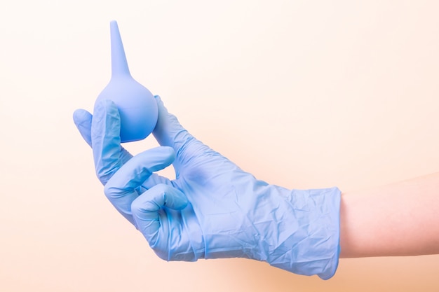 Daj niebieską rękawicę medyczną z niebieską lewatywą na świetle. medycyna, szczepienia, zdrowie. Minimalizm,.