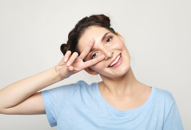 Daj szansę pokojowi Portret ładnej brunetki przedstawiającej znak pokoju na szarym tle