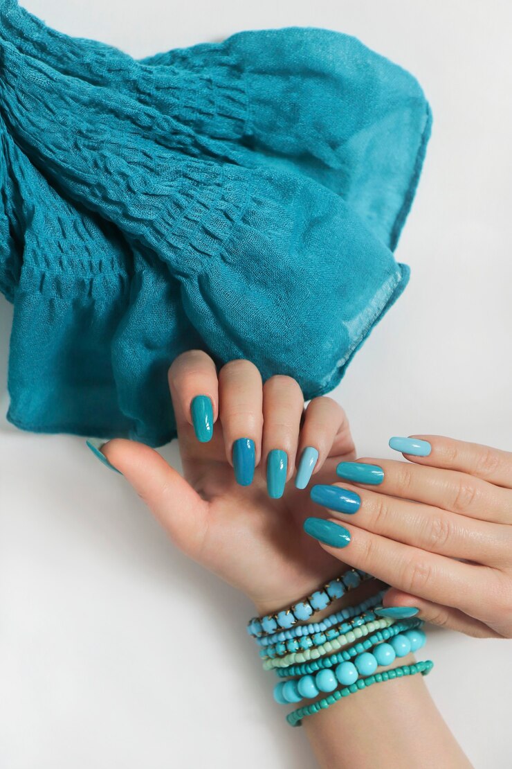 Damskie dłonie na jasnej powierzchni z niebieskim manicure i szalikiem