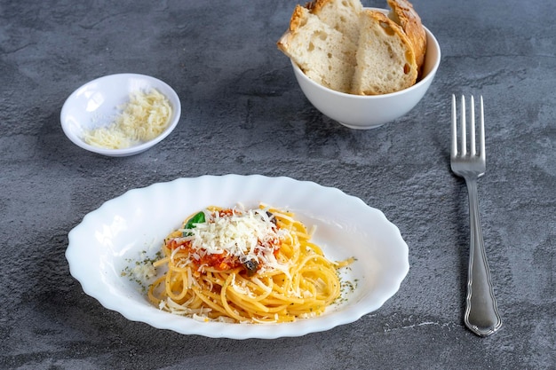 Danie do spaghetti z sosem amatriciana i parmezanem, w towarzystwie pieczywa i sera. Gotowy do jedzenia z widelcem