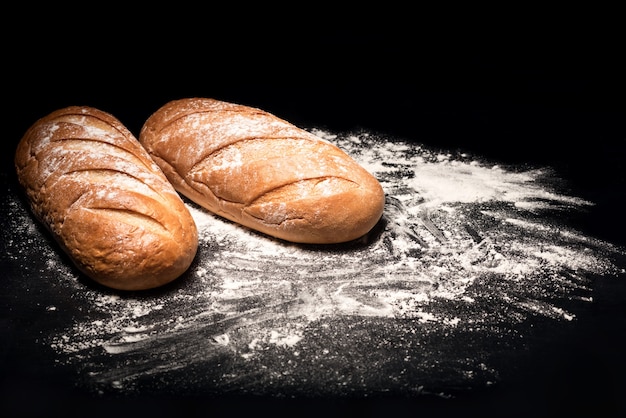 Danie podstawowe. Zamknij się z chleba leżącego na desce do krojenia podczas gdy jest posypany mąką