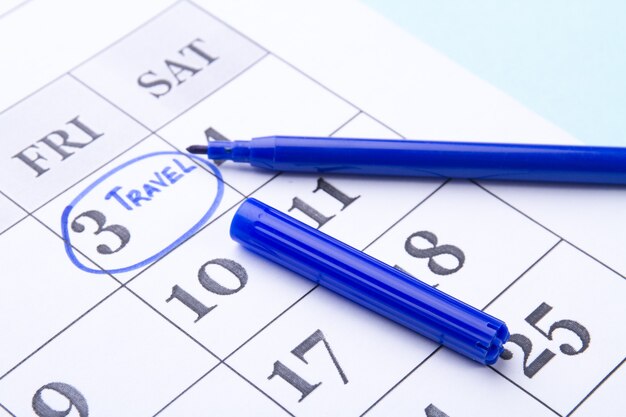 Data kalendarza zakreślona niebieskim piórem podróży koncepcja spotkania zbliżenie arkusz kalendarza