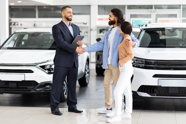 Zdjęcie dealer samochodowy i para uściskająca ręce w salonie wystawowym