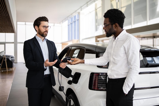 Dealer sprzedaje elektryczny SUV biznesmenowi w nowoczesnym salonie samochodowym