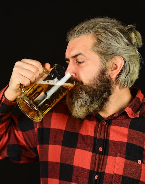 Zdjęcie degustacja piwa brutalnego hipster piwo dojrzały brodaty barman trzyma szklankę pewny siebie barman podnoszący toast rekreacja i świętowanie człowiek pijący piwo w pub bar piwo z pianką