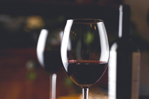 Degustacja wina Kieliszek czerwonego wina na tle restauracyjnego stołu z butelką podczas wieczornej kolacji lub imprezy okolicznościowej Zdjęcie wysokiej jakości