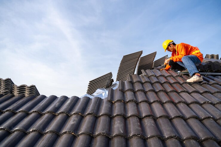 Dekarz montuje betonowy dach na nowych dachach, podczas gdy trwa budowa betonowych dachówek
