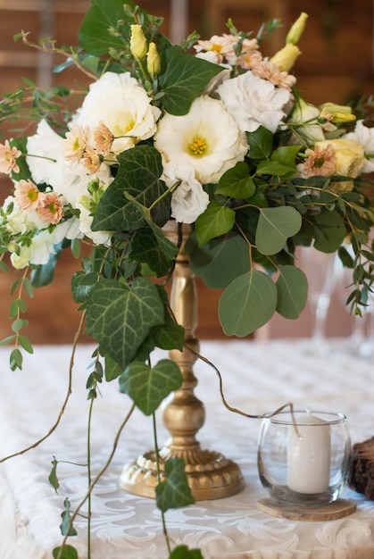 Dekoracja kwiatowa ceremonii ślubnej. Biało-brzoskwiniowa mieszanka kwiatów w złotym wazonie. Styl rustykalny.