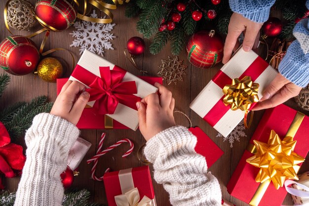 Dekoracja prezentów świątecznych tło Ręce matki i dziecka owijają stos na noworoczne i świąteczne pudełka z świątecznymi wstążkami przygotowanie do świąt bokserskich
