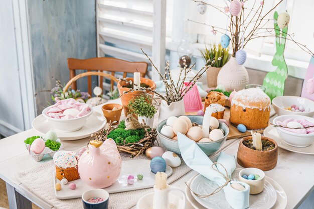 Dekoracja stołu na obchody wielkanocne w kuchniPejzaż stołu na święta wielkanocne w domuRodzina religijna tradycyjna świąteczna chrześcijaństwokatolicki posiłek jedzeniePop kolorowe jajkaciastozabawa króliczekcukierki słodkie