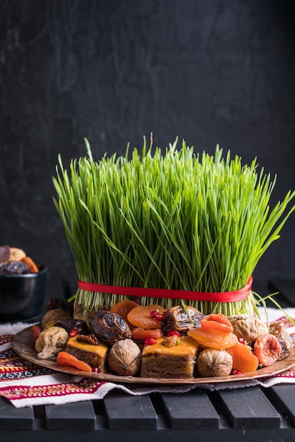Zdjęcie dekoracja stołu novruz, trawa pszeniczna, pakhlava z ciasta narodowego azerbejdżanu, świętowanie nowego roku, przebudzenie natury