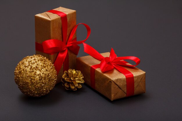 Dekoracja świąteczna. Pudełka na prezenty, zabawka piłka i naturalny stożek na czarnym tle. Koncepcja karty z pozdrowieniami świątecznymi.