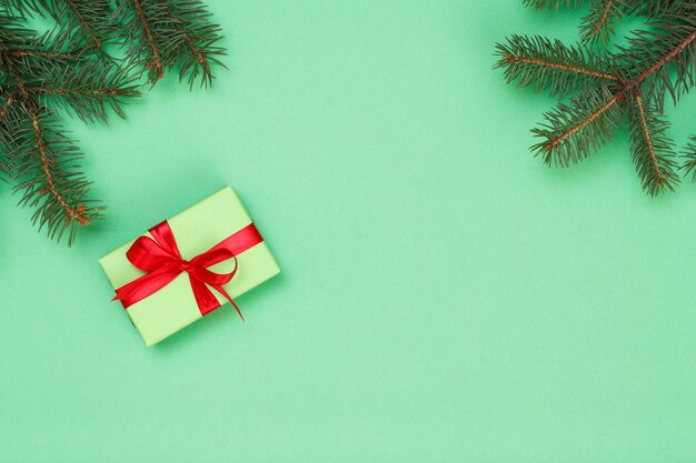 Dekoracja świąteczna. Pudełko z gałęzi drzewa wstążki i jodły na zielonym tle. Widok z góry. Koncepcja karty z pozdrowieniami świątecznymi.