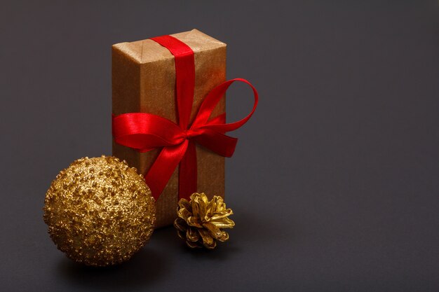 Dekoracja świąteczna. Pudełko, zabawka piłka i naturalny stożek na czarnym tle. Koncepcja karty z pozdrowieniami świątecznymi.