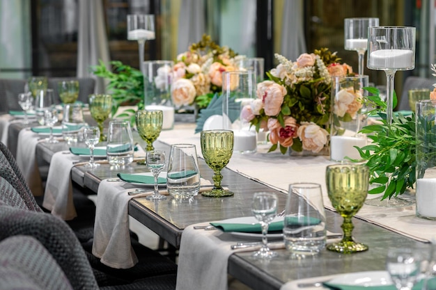 Dekoracja z zielonymi szklanymi kwiatami i świecami na weselny furshet