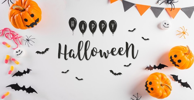 Dekoracje na Halloween wykonane z papierowych nietoperzy dyniowych, czarnego pająka i tekstu na pastelowym pomarańczowym tle