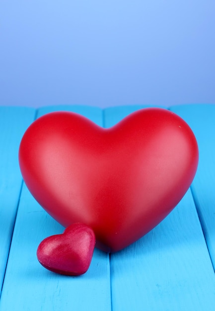 Dekoracyjne czerwone serca na niebieskim drewnianym stole na niebieskim tle
