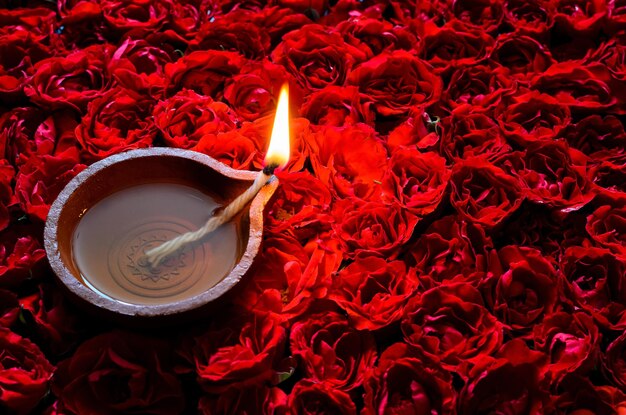 Dekoracyjny czerwony różowy kwiat rangoli na festiwal Diwali z glinianą lampą rozpaloną płomieniem