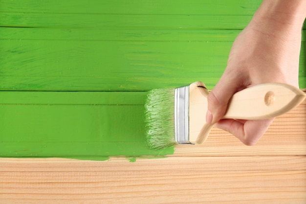 Dekorator maluje drewno zieloną farbą