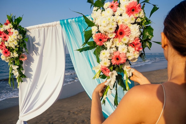 Dekorator pracujący z kompozycją kwiatów do łuku ślubnego na plaży nad oceanem