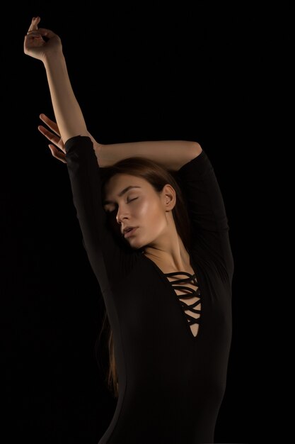 Delikatna brunetka kobieta z długimi włosami pozuje w cieniu w studio
