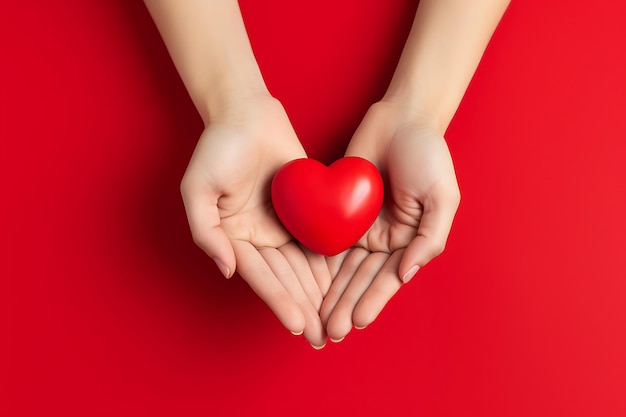 Delikatne dłonie kobiet trzymają czerwone serce na czerwonym tle Walentynki