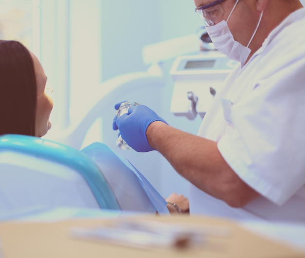 Zdjęcie dentyści płci męskiej badają i pracują nad młodą pacjentką gabinet dentystyczny