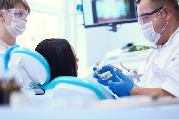 Dentyści płci męskiej badają i pracują nad młodą pacjentką