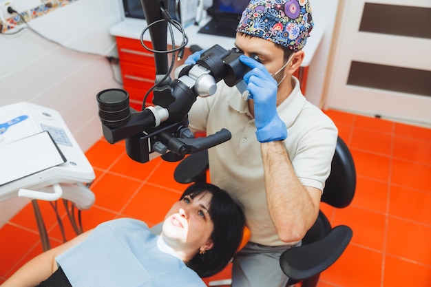 Dentysta bada jamę ustną pacjenta pod mikroskopem stomatologicznym leczenie stomatologiczne pojęcie mikroskopu zdrowych zębów w stomatologii