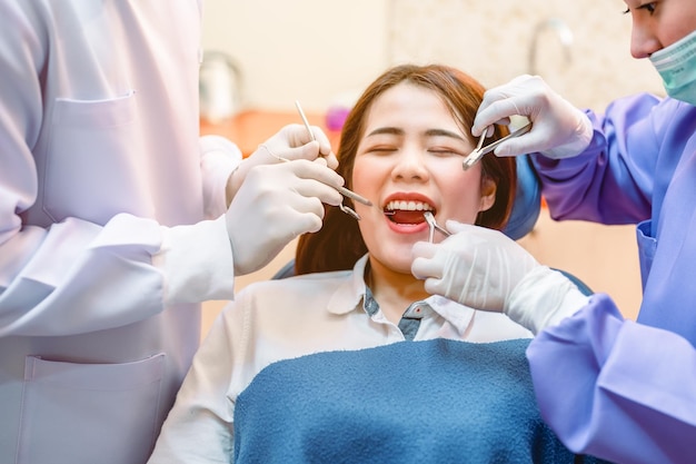 Dentysta bada pacjentów z zębami w klinice w celu lepszego zdrowia zębów i jasnego uśmiechu Dentysta wydobywa zęby mądrościNarzędzia i sprzęt dentystyczny