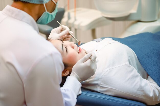 Dentysta bada pacjentów z zębami w klinice w celu lepszego zdrowia zębów i jasnego uśmiechu Dentysta zeskrobuje wapień Narzędzia i sprzęt dentystyczny