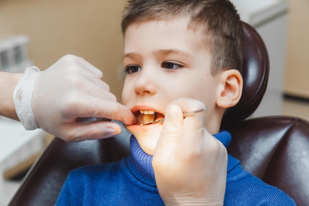 Dentysta bada zęby małego chłopca, pacjenta w klinice dentystycznej