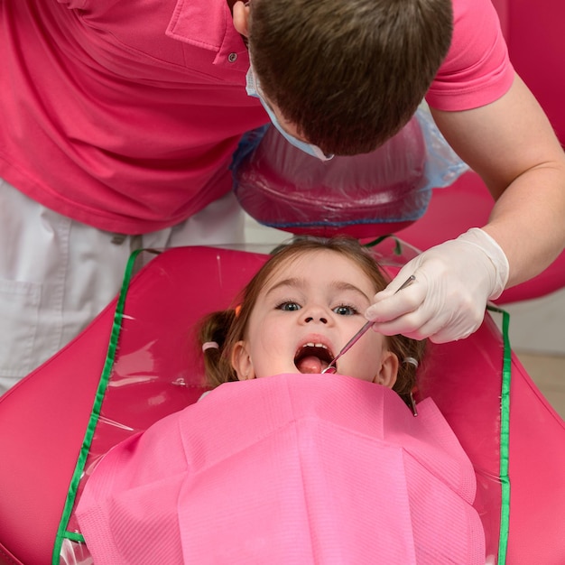 Dentysta bada zęby niemowlęce dziewczynki leczenie zębów mlecznych dentysta trzyma lusterko