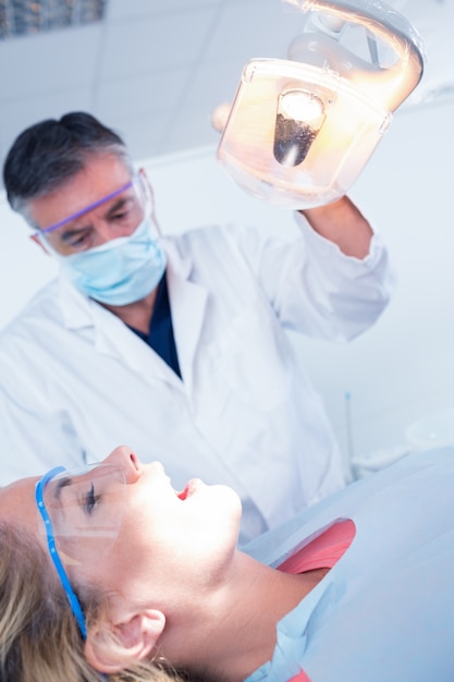 Dentysta bada zęby pacjentów w fotelu w jasnym świetle