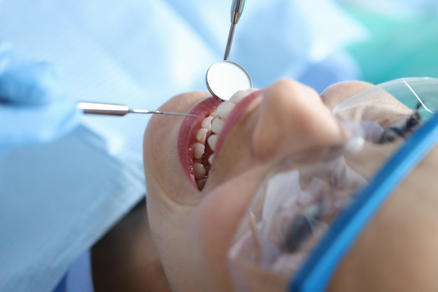 Dentysta Badający Jamę Ustną Pacjenta Kobiety W Klinice Za Pomocą Narzędzia Zbliżenie