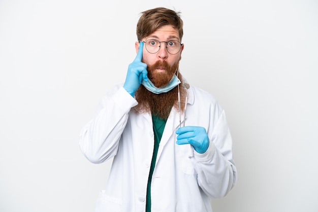 Dentysta czerwonawy mężczyzna trzymający narzędzia na białym tle myślący o pomyśle