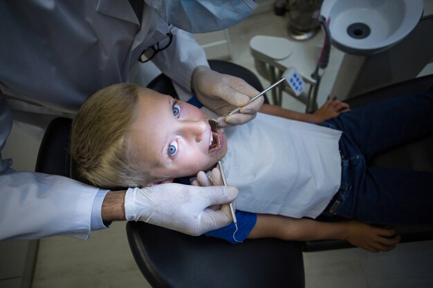 Dentysta egzamininuje młodego pacjenta z narzędziami