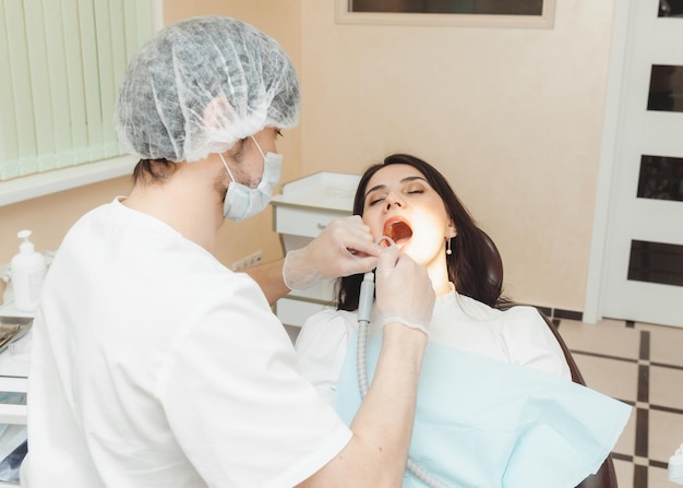 Dentysta i pacjent w gabinecie stomatologicznym Lekarz leczy zęby młodej kobiety wiertłem Higiena i zdrowe zęby
