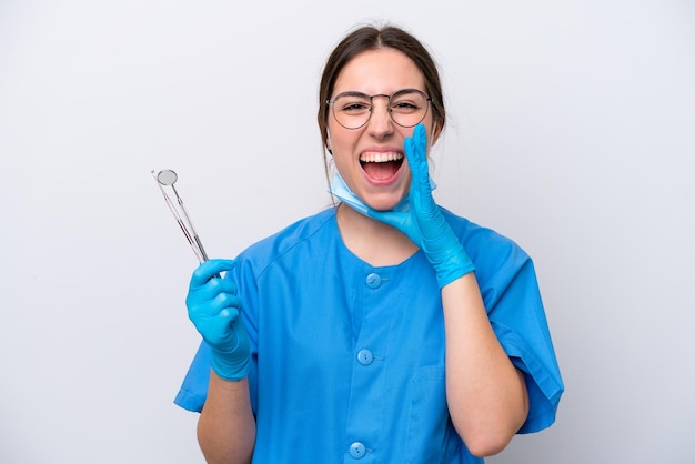 Dentysta kaukaska kobieta trzymająca narzędzia na białym tle krzycząca z szeroko otwartymi ustami