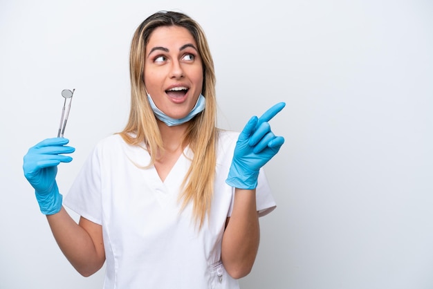 Dentysta kobieta trzymająca narzędzia na białym tle zamierzająca zrealizować rozwiązanie, podnosząc palec w górę