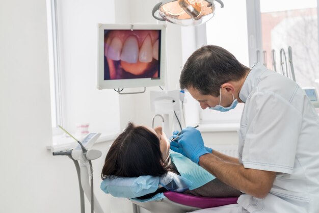 Dentysta leczący zęby pacjenta instrumentami w stomatologii