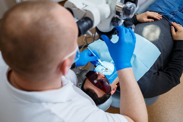 Dentysta leczy zęby swojego pacjenta pod mikroskopem. Dentysta leczy usta pacjenta. Opieka dentystyczna. Zdjęcie wysokiej jakości