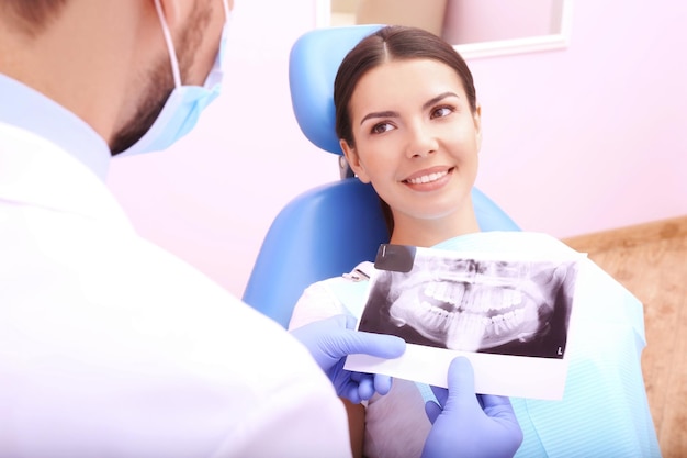 Dentysta patrzący na zdjęcie rentgenowskie zębów młodej kobiety