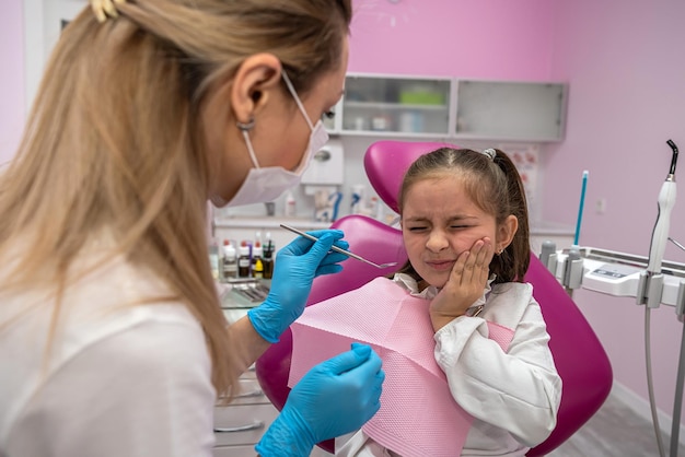 Dentysta pediatra kobieta otrzymuje małą piękną dziewczynę w recepcji
