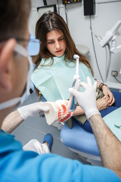 Dentysta pokazujący klientowi technikę czyszczenia zębów.