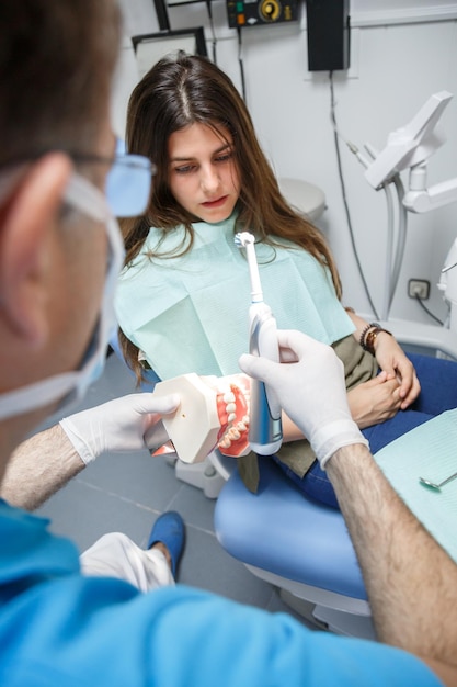 Dentysta pokazujący klientowi technikę czyszczenia zębów.
